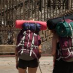 Escursionisti lungo il Cammino di Santiago con paesaggio italiano sullo sfondo.