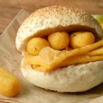 Deliziosi piatti di street food siciliano, tra cui arancini e pane con la milza, esposti su un mercato.